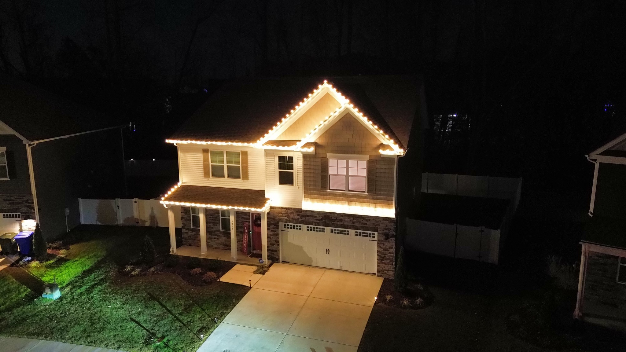 Professional warm white Christmas lights outlining a two-story home